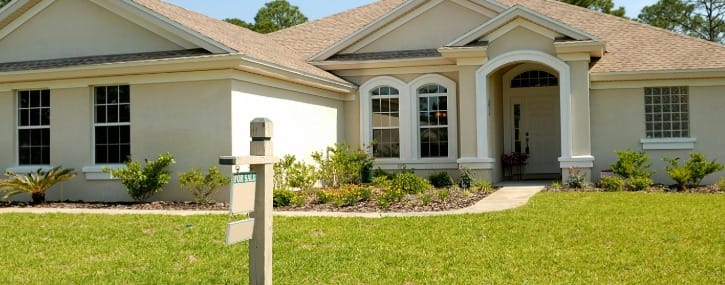 Image shows a for sale sign in front of a house