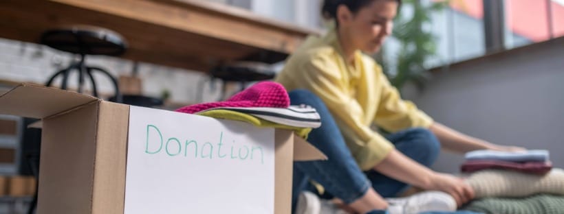 Homeowner organizing and packing gently used items into a donation box at home